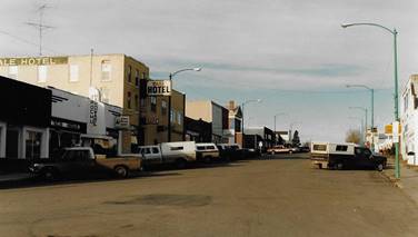 A street with cars parked in front of buildings
Description automatically generated